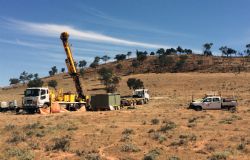 Commencement of diamond drilling at Pyrite Hill with outcropping mineralisation exposed along ridge in background.